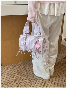 Detailed shot of a stylish light purple Boston handbag featuring chic rivets and cute charms.