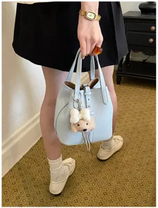 Hellblaue Leder Eimer Tasche Detail mit süßem Plüsch Welpen Anhänger, stilvolle Handtasche.