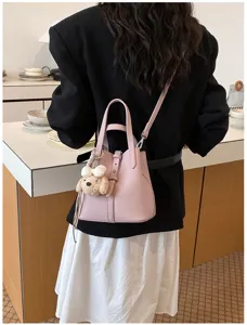 Elegante rosa Eimer-Tasche für Damen, mit Tragegriff und Umhängeriemen und süßem Hunde-Anhänger.