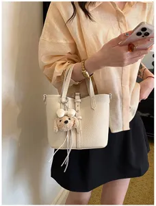 Detailaufnahme der schicken beigen Beuteltasche mit süßem Bärenanhänger für die sommerliche Freizeit.