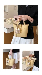 Detailansicht der gelben Leder-Eimer Tasche mit süßem Welpen-Anhänger und Schultergurt.