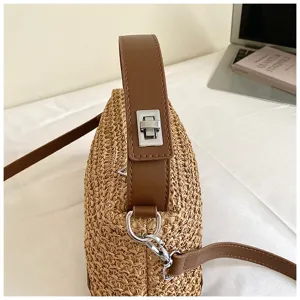 Vista detallada del elegante bolso cruzado de paja con asa de marrón cuero y cierre metálico.