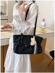 Vue détaillée du sac cabas souple noir avec un charmant pendentif en peluche de chiot.
