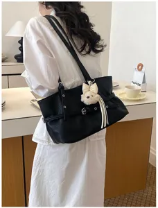 Détail du sac cabas souple noir avec œillets métalliques et charmant pendentif ours en peluche.