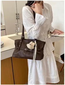Détail de sac à épaule en cuir souple marron, style sac sous les bras élégant.