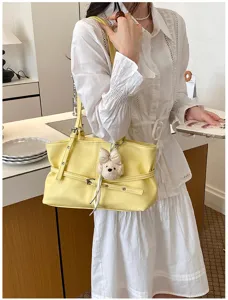 Vue rapprochée du sac cabas souple jaune porté à l'épaule, mettant en valeur son style élégant.