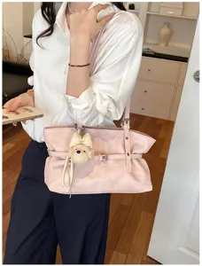 Gros plan détaillé du sac cabas en cuir souple rose avec joli charm ours et porté épaule.
