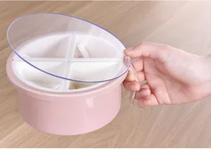 Detail shot of a pink 4-grid kitchen seasoning box with clear lid and hand holding handle.