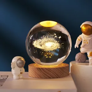 Galaxy crystal ball night light with wooden base and astronaut decor for bedroom interior.