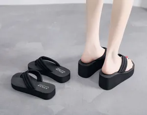 Vue détaillée de tongs compensées noires pour femmes avec bride épaisse pour la plage.