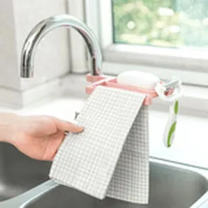 Kitchen faucet storage rack detail showing soap holder and towel hanging in sink area.