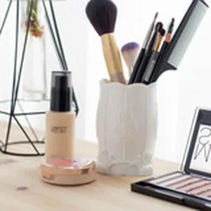 Detailed view of a vintage white ceramic makeup brush holder and cosmetics desktop organizer.