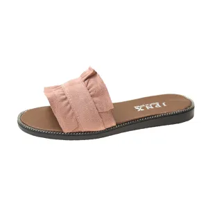 Close-up detail of the pink ruffled flat slide sandal showing soft suede texture and sole trim.