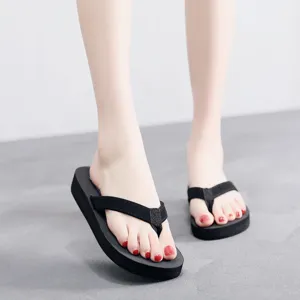 Gros plan détail de tongs compensées noires pour femmes, sandales de plage confortables.