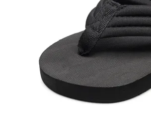 Détail de tong compensée noire montrant la semelle texturée et la bride en tissu.