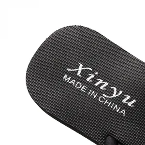 Close-up of black rubber flip flop sole with anti-slip texture and printed branding text.