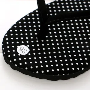 Schwarze gepunktete Zehentrenner Detailaufnahme im Sommer Strandmode Design Stil.