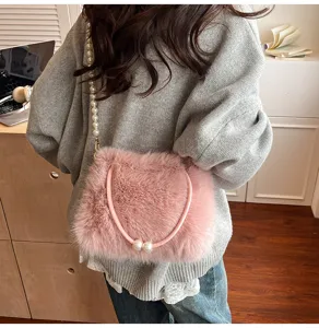 Detailed view of a trendy pink faux fur shoulder bag with pearl strap, cozy and stylish look.