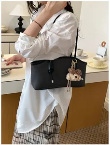 Detailansicht der schicken schwarzen Baguette-Achseltasche mit niedlichem Plüsch-Hundeanhänger.