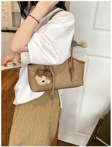 Detailansicht der stylischen braunen Baguette Umhängetasche mit süßem Bären Anhänger.