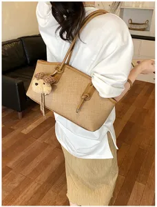 Detailansicht der stylischen braunen Schultertasche mit süßem Bärenanhänger für den Alltag.