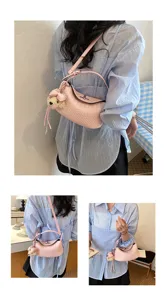 Detailed view of the pink woven leather crossbody bag featuring a cute fluffy bear pendant.