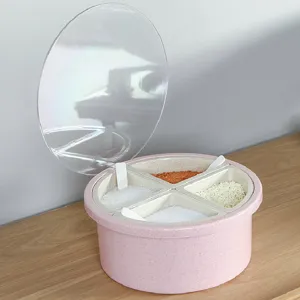Pink round four-grid kitchen seasoning box with clear lid and small spoons for home storage.