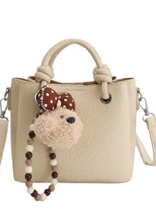 Beige leather bucket bag for women, casual crossbody handbag with cute fluffy bear plush pendant.