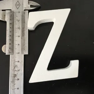 Detail view of the white wooden letter Z being measured with a caliper for size check.