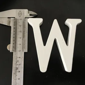 White wooden letter W ornament, detail shot showing precise size with caliper tool for decor.