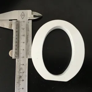 Detailed view of white wooden letter ornament with caliper measuring size for home decor props.