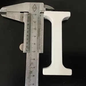 White wooden letter I decorative ornament detail view showing dimensions with caliper tool.