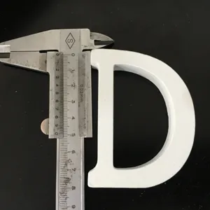 Close-up detail of white wooden letter D ornament prop being measured with a metal caliper.