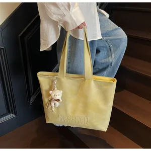 Detail view of large capacity casual tote bag, simple design with cute bear pendant for women.