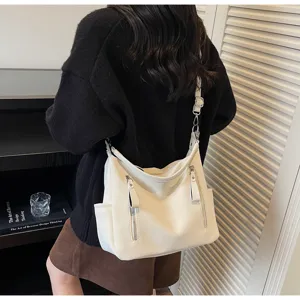 Detail shot of stylish white shoulder bag with zipper pockets, casual commuter design.
