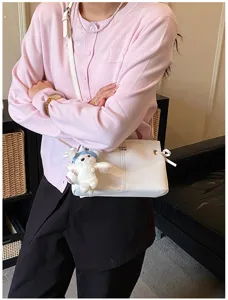 Minimalist white crossbody bag for women, stylish shoulder bag with cute bear pendant.