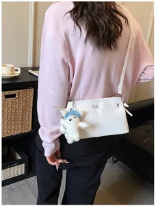 White leather shoulder bag detail, stylish crossbody bag with cute bear pendant and bow.