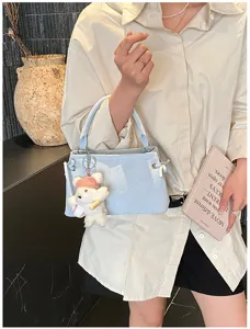 Light blue fashion handbag detail view, elegant commute style with cute bear charm accent.