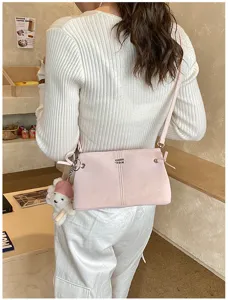 Minimalist pink leather shoulder bag detail, chic crossbody bag with cute bear pendant for women.