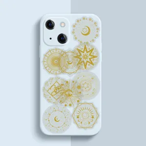 Detailaufnahme einer weißen Handyhülle mit goldener astrologischer Sonne und Mond Deko.