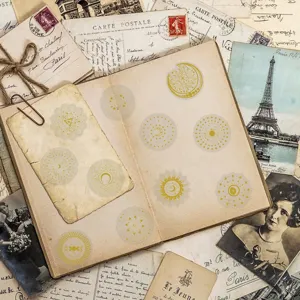 Detailaufnahme von vergoldeten Himmelsaufklebern mit Mond- und Sonnendesigns auf einem alten Tagebuch.