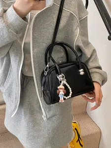 Black patent leather Boston bag for women, stylish crossbody handbag with cute charm.