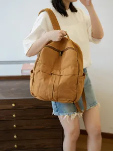 Détail de sac à dos en toile marron durable, avec poche zippée et espace de rangement latéral.