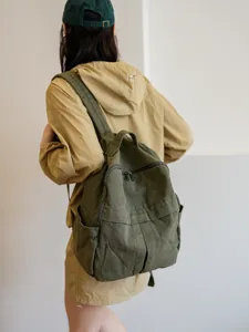 Vue détaillée du sac à dos en toile vert foncé porté par le modèle, style décontracté.
