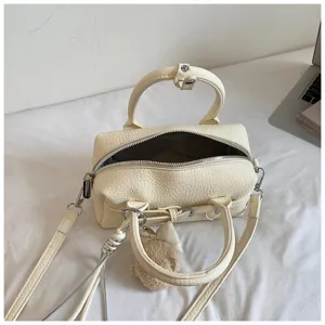 Primo piano sui dettagli della borsa da bowling in pelle crema con cerniera e manici.