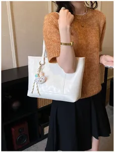 Detail view of a stylish white commuter tote bag with cute charm, perfect for daily use.