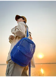 Detailed scene of a blue mesh backpack outdoors at sunset, breathable fabric, casual travel style.