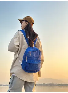 Outdoor scene detail of a breathable blue mesh backpack for summer travel and beach use.