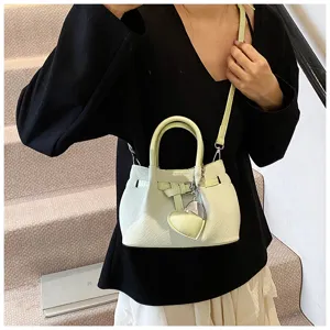 Close-up detail of the stylish light green woven bucket bag with cute heart pendant and strap.