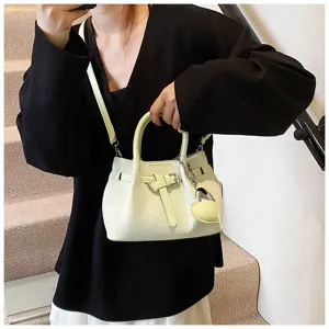 Detailed view of trendy pleated bucket bag with heart pendant, stylish light green finish.